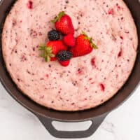 berry skillet cake with whole berries on top and recipe name at the bottom