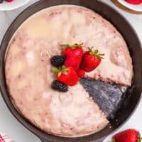 square image of berry skillet cake with lemon glaze with a slice cut out