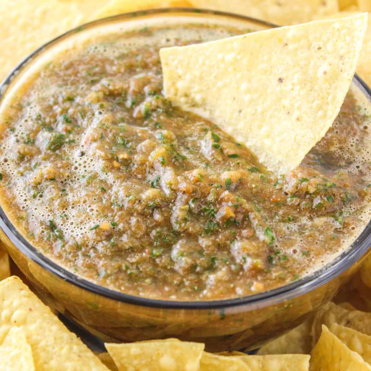 square close up image of easy blender salsa in a bowl with a tortilla chip