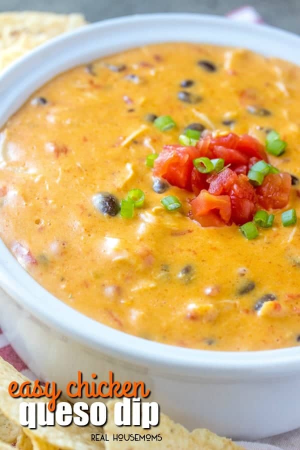 Easy chicken queso dip in a serving bowl topped with diced tomato and green onion