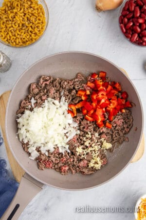 mostly cooked ground beef in a skillet with onions, red bell pepper, and garlic