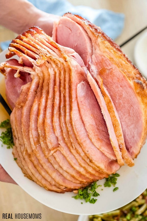 person holding spiral cut ham on a platter