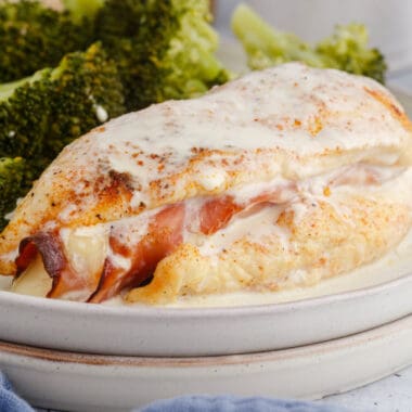 square imgae of ham & cheese stuffed chicken with mustard cream sauce on a plate with broccoli