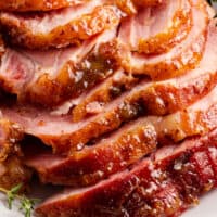close up of a glazed spiral ham on a platter with text at the bottom