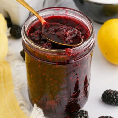 square image of a spoonful of homemade blackberry sauce resting on the mason jar