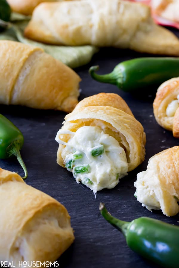 Jalapeno Popper Crescent Roll split in half to show the creamy, cheesy filling with diced jalapenos