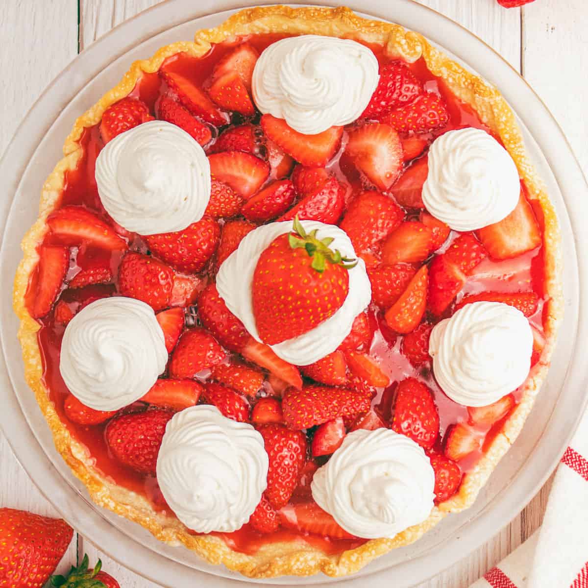 square image of easy strawberry pie recipe topped with dollops of whipped cream