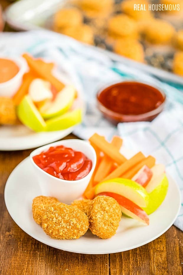 Plate of MorningStar Farms Chik'n Nuggets with ketchup, carrots, and apples