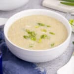 square image of a bowl of egg drop soup topped with sliced green onions