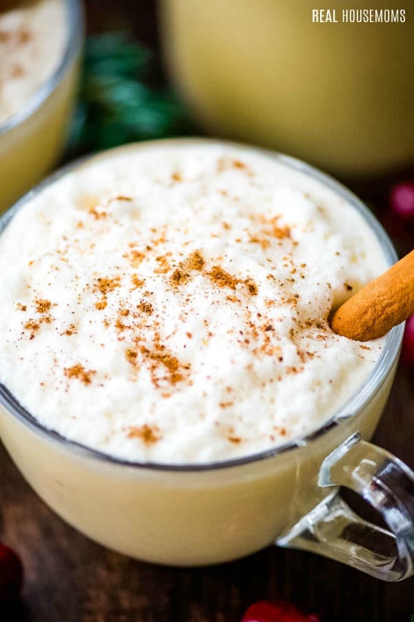close up of eggnog in a mug garnished with a cinnamon stick