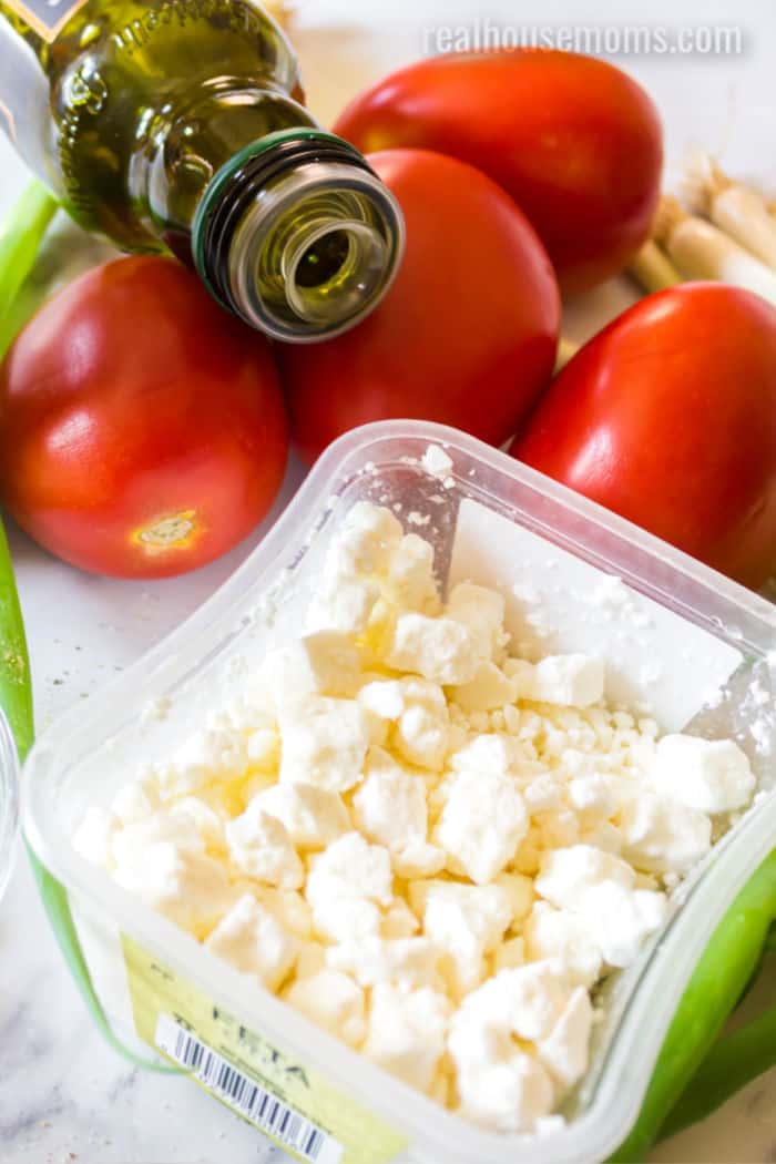 olive oil bottle, roma tomatoes, green onion, and crumbled feta cheese