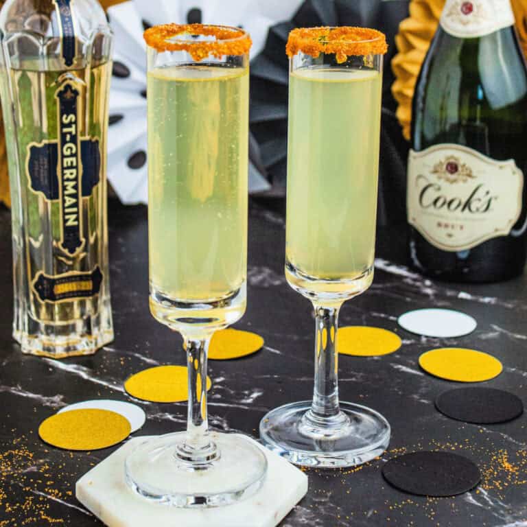 square image of two french 77 cocktails next to a bottle of st. germain and bottle of champagne