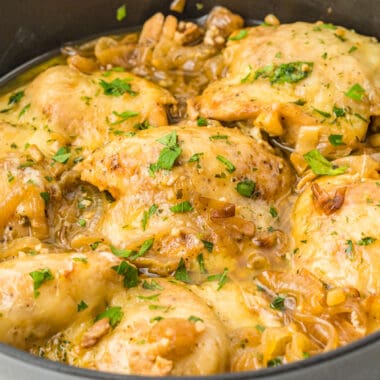 square image of french onion chicken thighs in a skillet with chopped parsley on top