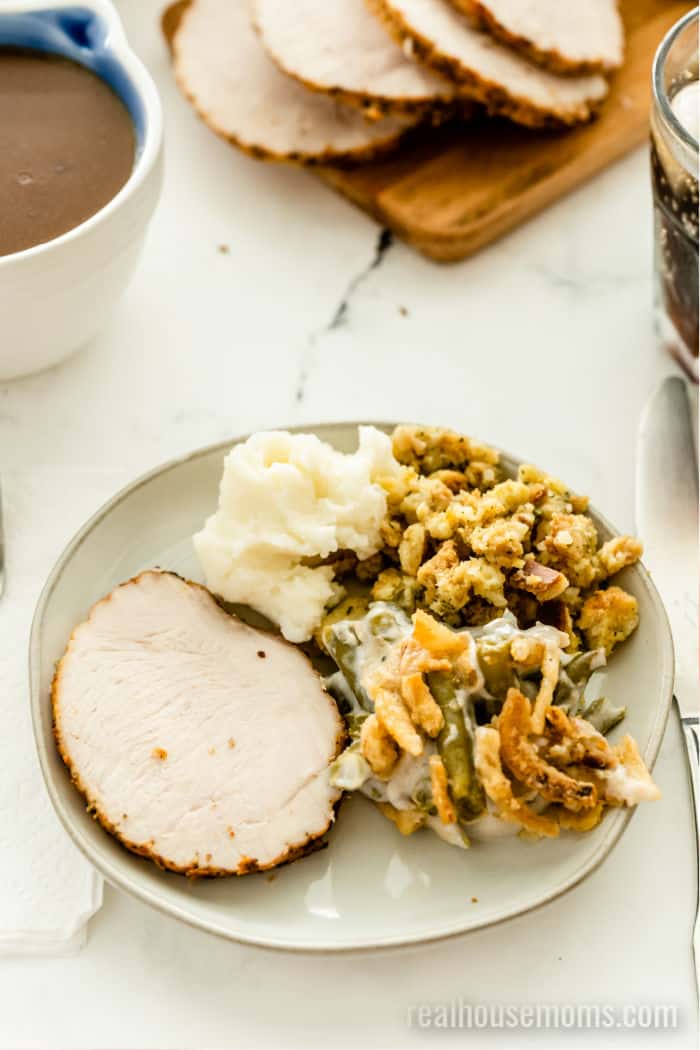 slices of turkey roast, mashed potatoes stuffing, and green bean casserole on a plate