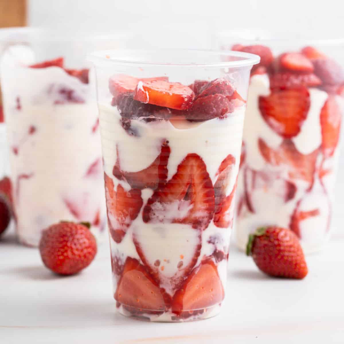 square image of three cps of fresas con crema next to some strawberries