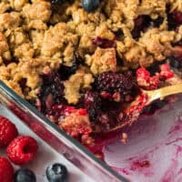 spoonful of fresh berry crisp resting in the dish with recipe name at the bottom