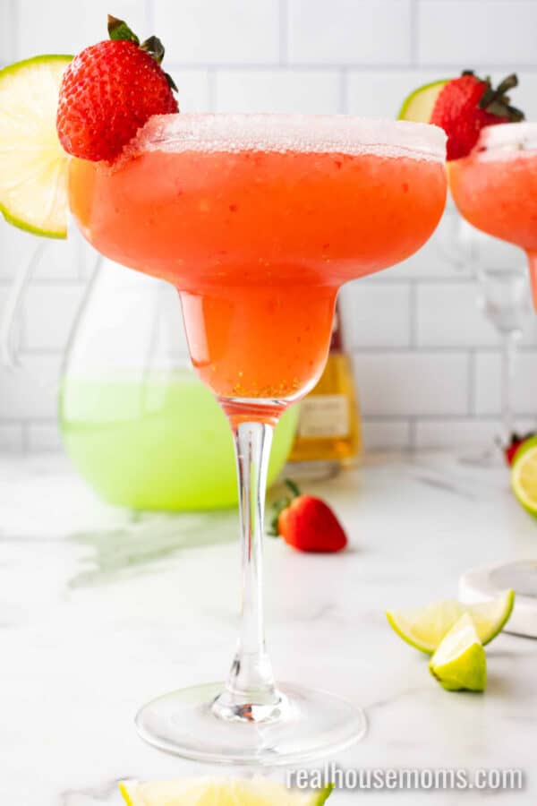 fresh strawberry margarita in a glass with a lime slice and strawberry for garnish