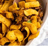 spoonful of frito pie being lifted from the casserole dish with recipe name at the bottom