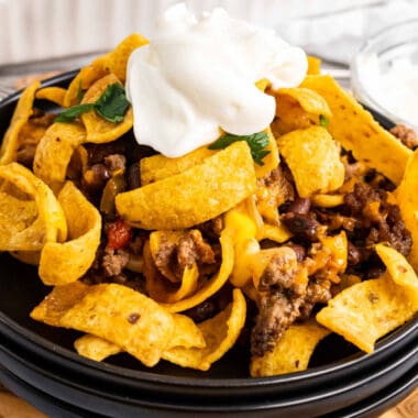 square image of frito pie topped with sour cream on a plate