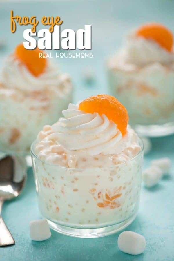 A dish of Frog Eye Salad topped with whipped cream and a Mandarin orange slice