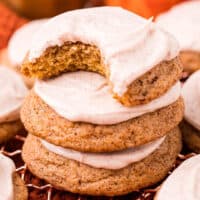 square image of frosted pumpkin snickerdoodles in a stack with a bite taken out of the top cookie