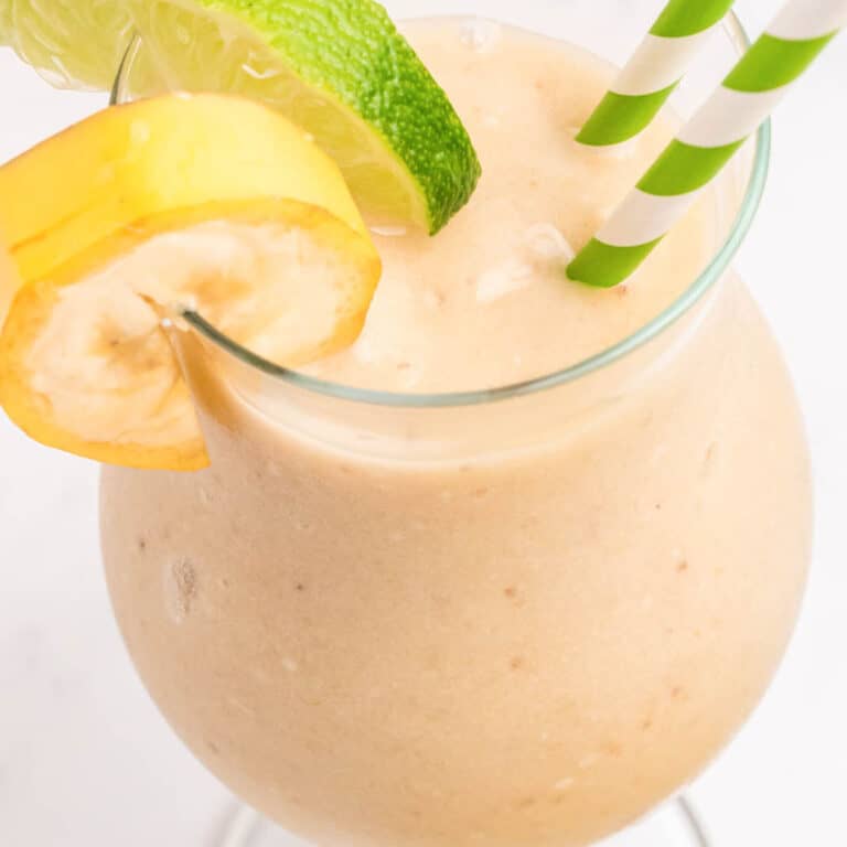 square image looking down into a frozen banana daiquiri with straws and fruit garnish