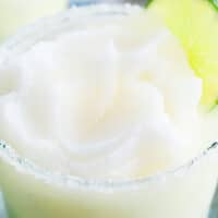 CLOSE UP OF BLENDED MARGARITA IN A GLASS WITH A LIME GARNISH