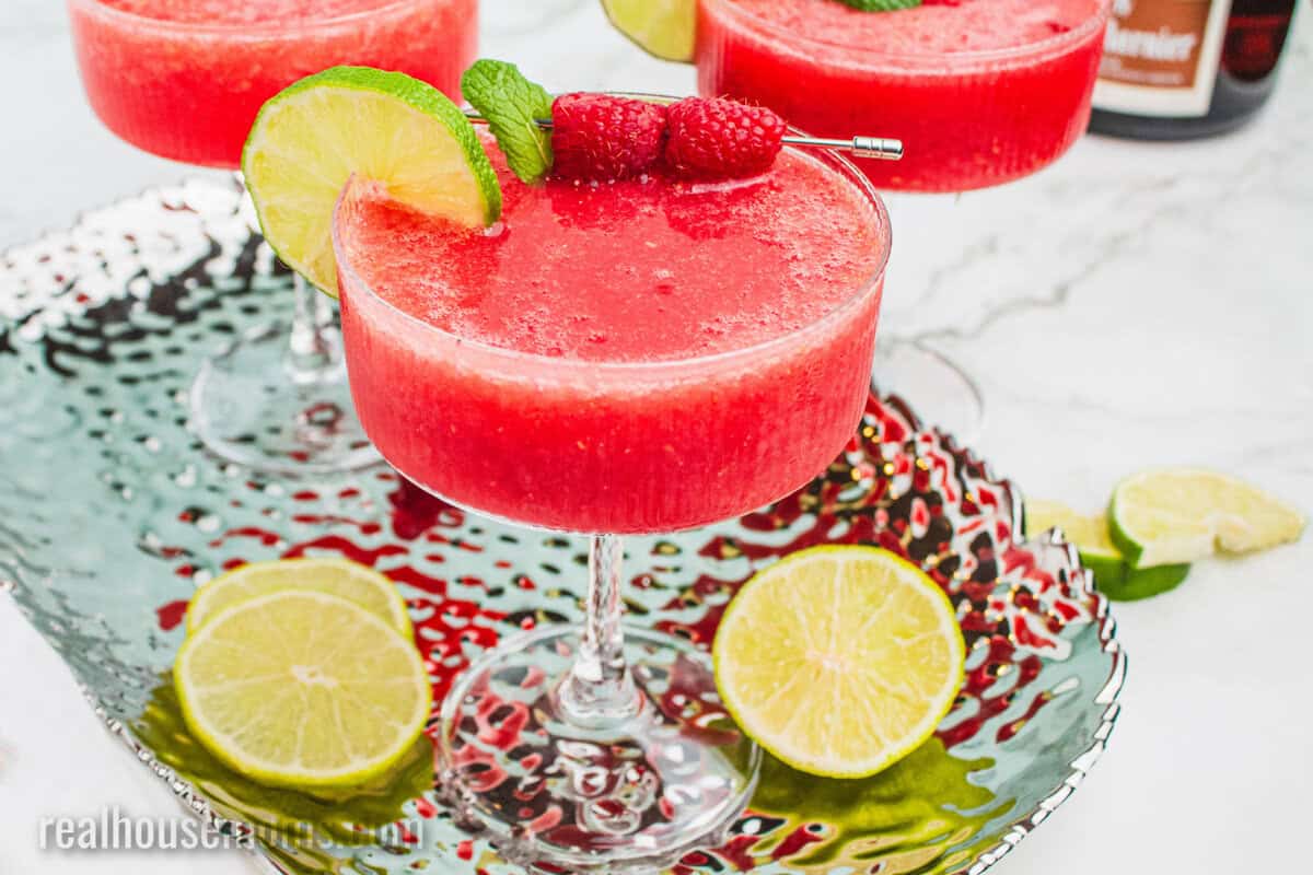 blended raspberry margarita on a silver tray next to a bottle of grand marnier