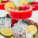 square image of a frozen raspberry margarita garnished with a lime slice and fresh raspberries on a cocktail pick