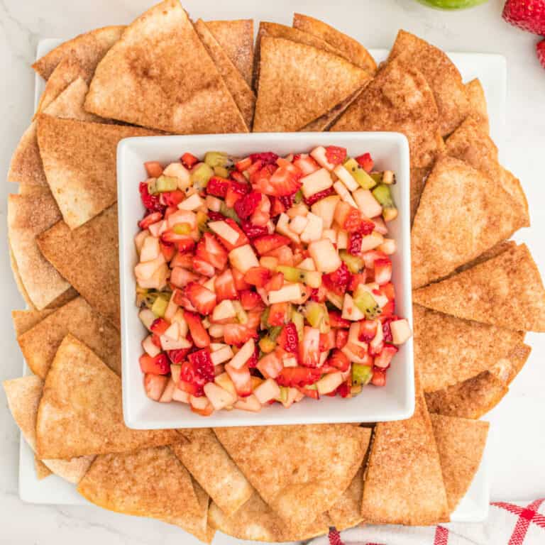 square image of fruit salsa in a bowl surrounded by cinnamon sugar chips