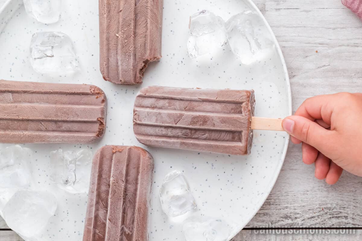 hand taking a fudgesicle from a platter