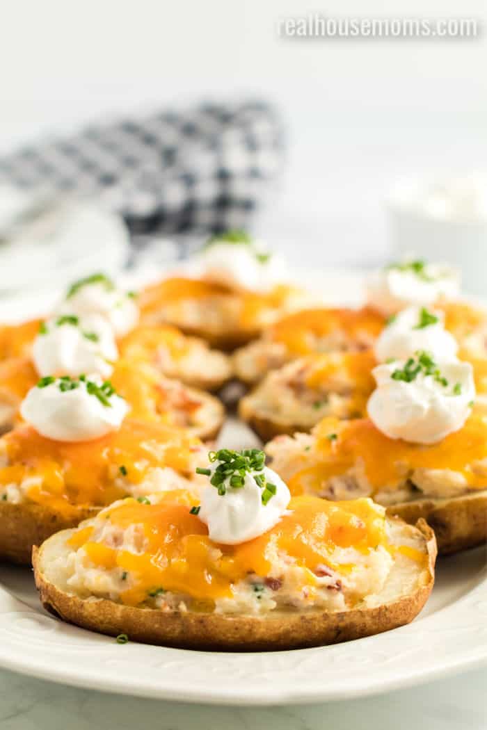 twice baked potatoes with cheese, sour cream, and chives on a platter