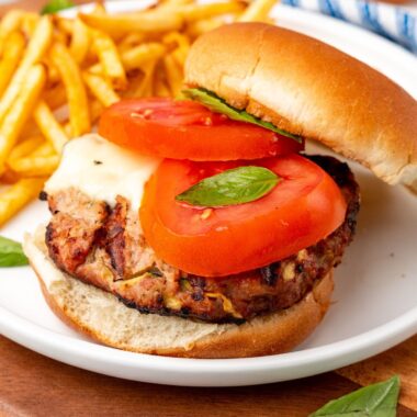square image of a caprese turkey burger on a plate with fries
