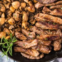 garlic butter steak & mushrooms in a cast iron skillet with recipe name at the bottom