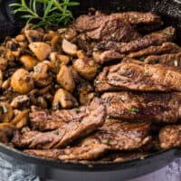 square image of garlic butter steak & mushrooms in a skillet