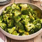 square image of garlic roasted broccoli in a serving bowl