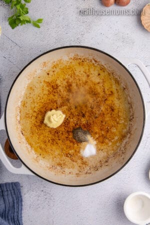 appl e cider vinegar, sugar, dijon, and pepper added to a skillet with bacon grease