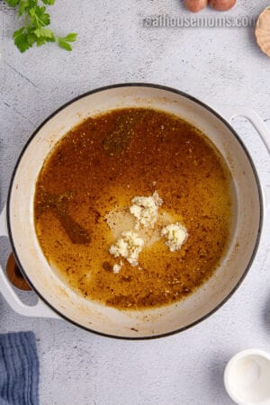 minced garlic added to the german potato salad dressing base in a large skillet