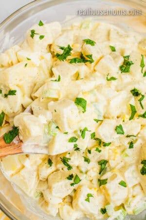 close up of grandma's best potato salad recipe topped with copped parsley after chilling in the fridge