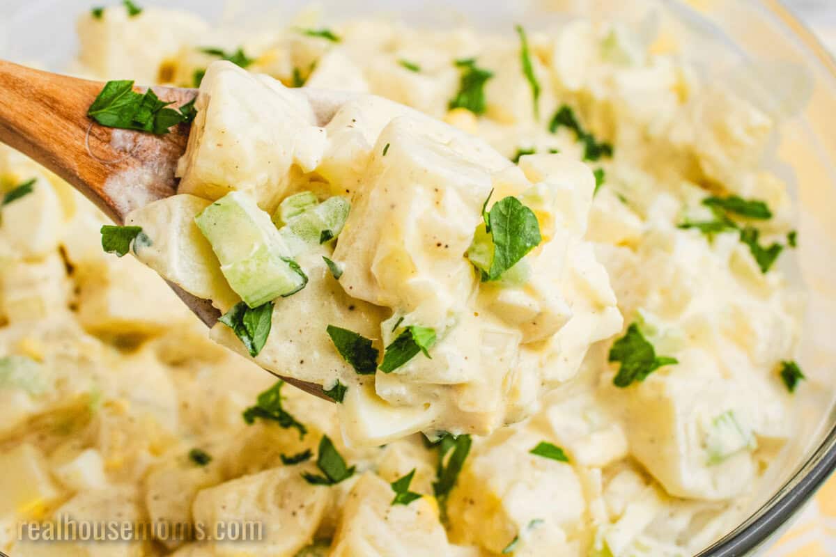 spoonful of grandma's best potato salad over the serving bowl
