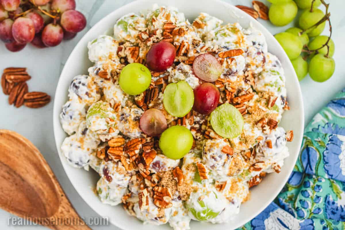 looking down at a bowl of grape salad topped with brown sure and pecans