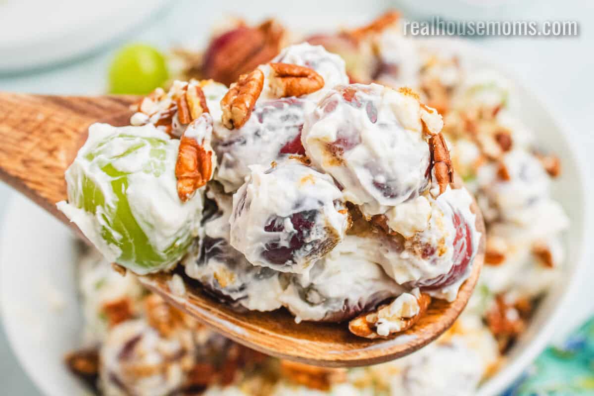 close up of a spoonful of grape salad over the serving bowl