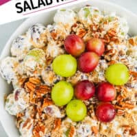 image of grape salad toped with extra red and green grapes in a serving bowl with the title of the post on top left of the picture