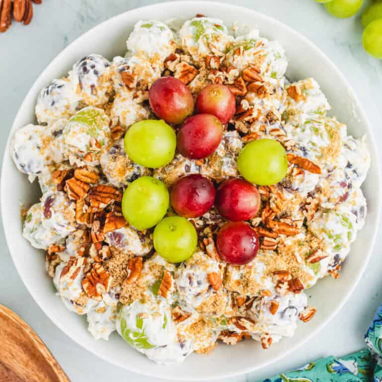 square image of grape salad toped with extra red and green grapes in a serving bowl