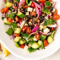 greek salad in a serving bowl with recipe name at the bottom