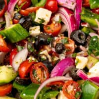 close up image of greek salad in a serving bowl with the title of the post on top of the image in pink and black lettering