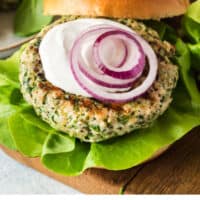 greek turkey burger with the bun resting on the edge, recipe name at the bottom