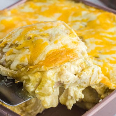 slice of chicken enchilada casserole being taken out of a pan