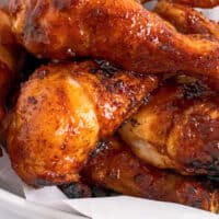 close up of grilled bbq chicken legs piled up with recipe name at bottom