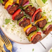 two grilled chicken fajita skewers over rice with recipe name at the bottom